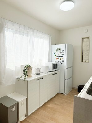 Eine kleine Küche mit Kühlschrank, Mikrowelle und Kaffeemaschine auf der Arbeitsfläche.