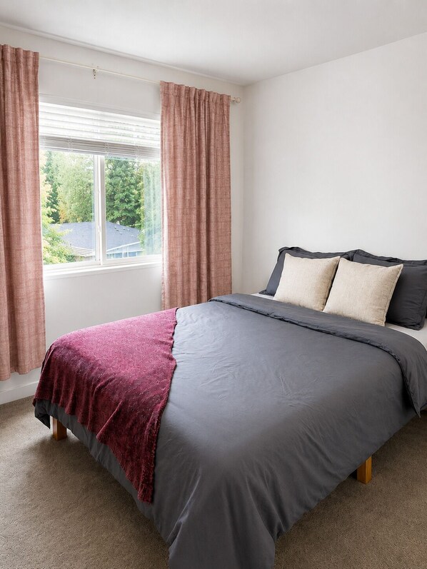 A bedroom with a bed, curtains, and a window.