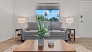 A living room with a grey sofa, two side tables, a wooden coffee table, a potted plant, and a view through a window. - Bright Mesa Getaway Near Dining and Shopping (Mesa)
