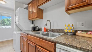 A kitchen with wooden cabinets, a granite countertop, a double sink, a coffee maker, and a dish rack. - Bright Mesa Getaway Near Dining and Shopping (Mesa)