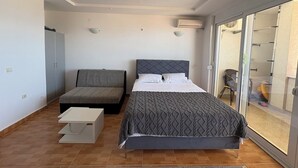 A bedroom with a bed, a sofa, a small table, and a sliding glass door to a balcony. - Perfect cozy apartment close to the Old town/Small beach/Women only beach (Ulcinj)
