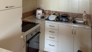 A kitchen with white cabinets, a stove, an oven, a microwave, and a sink. - Perfect cozy apartment close to the Old town/Small beach/Women only beach (Ulcinj)