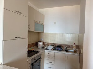 Eine kompakte Küche mit Herd, Backofen, Mikrowelle und kleinem Spülbecken.