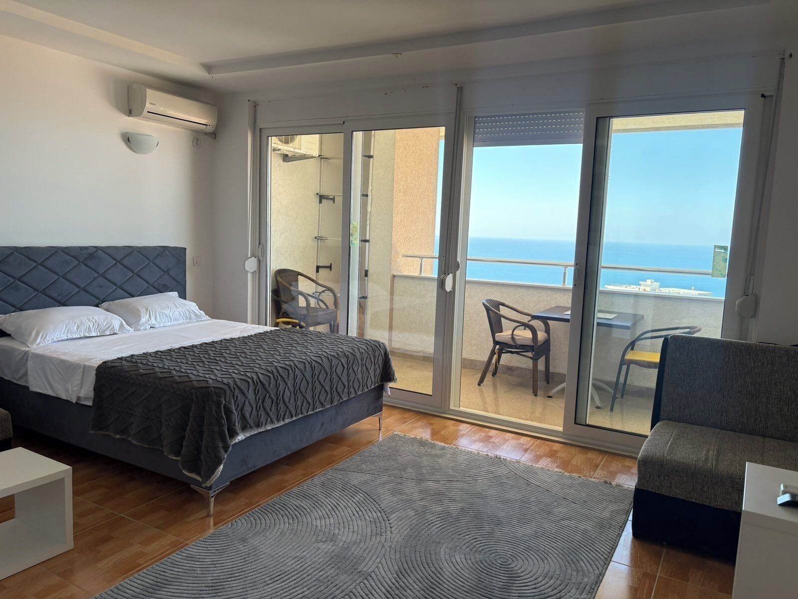 Une chambre avec un lit, une petite table, une chaise et un balcon donnant sur la mer.