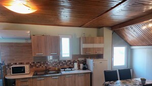 Una cocina compacta con armarios de madera, microondas, refrigerador y un comedor con mesa y sillas.