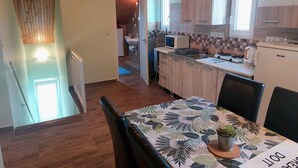 Una cocina con armarios de madera, una mesa de comedor con mantel estampado y una pequeña planta en maceta.