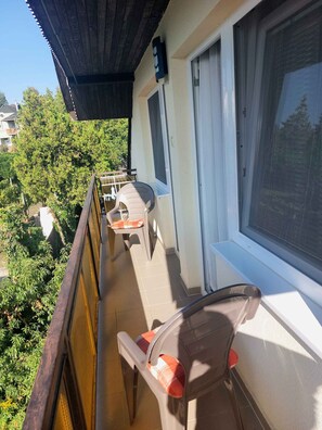 Un balcon avec une balustrade en bois, une chaise et une table.