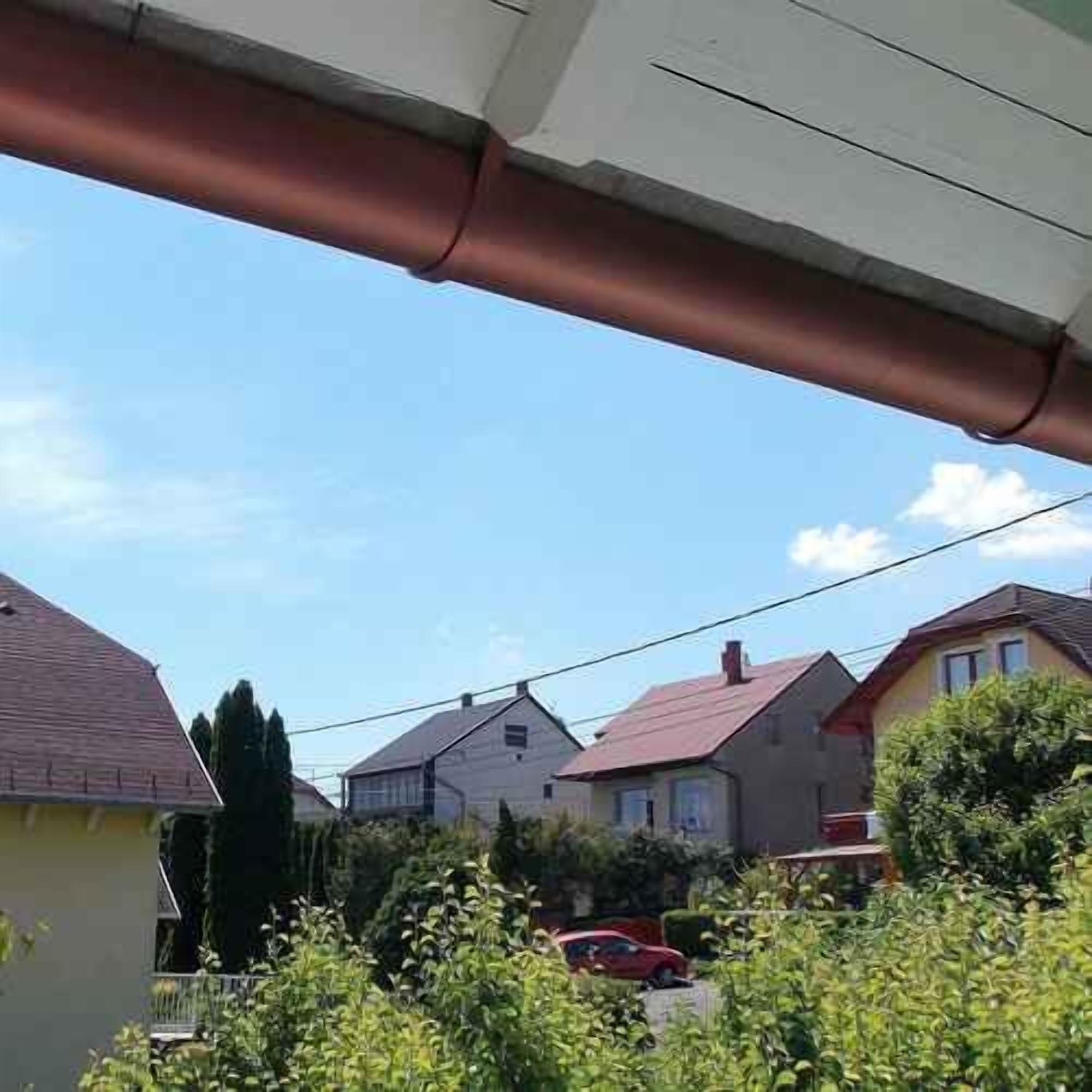 Un quartier résidentiel avec des maisons, une voiture rouge et un ciel dégagé.
