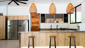 Een moderne keuken met roestvrijstalen apparatuur, houten kastjes en drie hangende pendelverlichting.