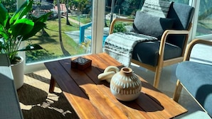 A room with large windows, a wooden table, a chair, and a potted plant. - Beachfront Penthouse w Rooftop Pools Views (Punta Cana)