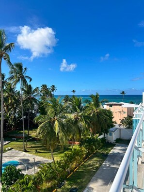 Blick auf ein Strandgrundstück mit Palmen, einem Pool und blauem Himmel.