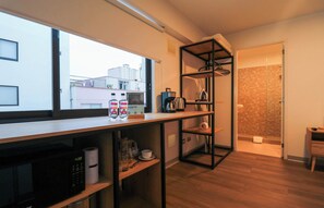 Eine moderne Küche mit Kaffeemaschine, Wasserkocher und Mikrowelle. Ein Fenster bietet Blick auf die Stadt.