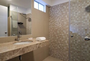 Ein Badezimmer mit Duschkabine, Waschbecken mit Spiegel und einem Handtuch auf der Ablagefläche.