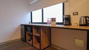 Een kitchenette met een raam, een koffiezetapparaat en een waterkoker.