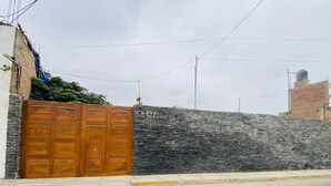 Una entrada con reja, pared de piedra y un cartel con el número de la dirección.