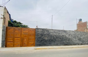 Una entrada con reja, pared de piedra y un cartel con el número de la dirección.