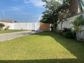 Um bairro residencial com um caminho de acesso pavimentado, cerca branca e um edifício de tijolos com porta de madeira.