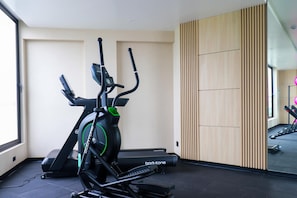 A gym with stationary bikes and treadmills, a wooden panel wall, and a large window. - w* | Scenic 2BR w/ Balcony & View in Miraflores (Miraflores)
