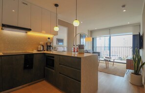 Eine moderne Küche mit integrierten Geräten, ein Essbereich mit Tisch und Stühlen sowie ein Balkon mit Blick.