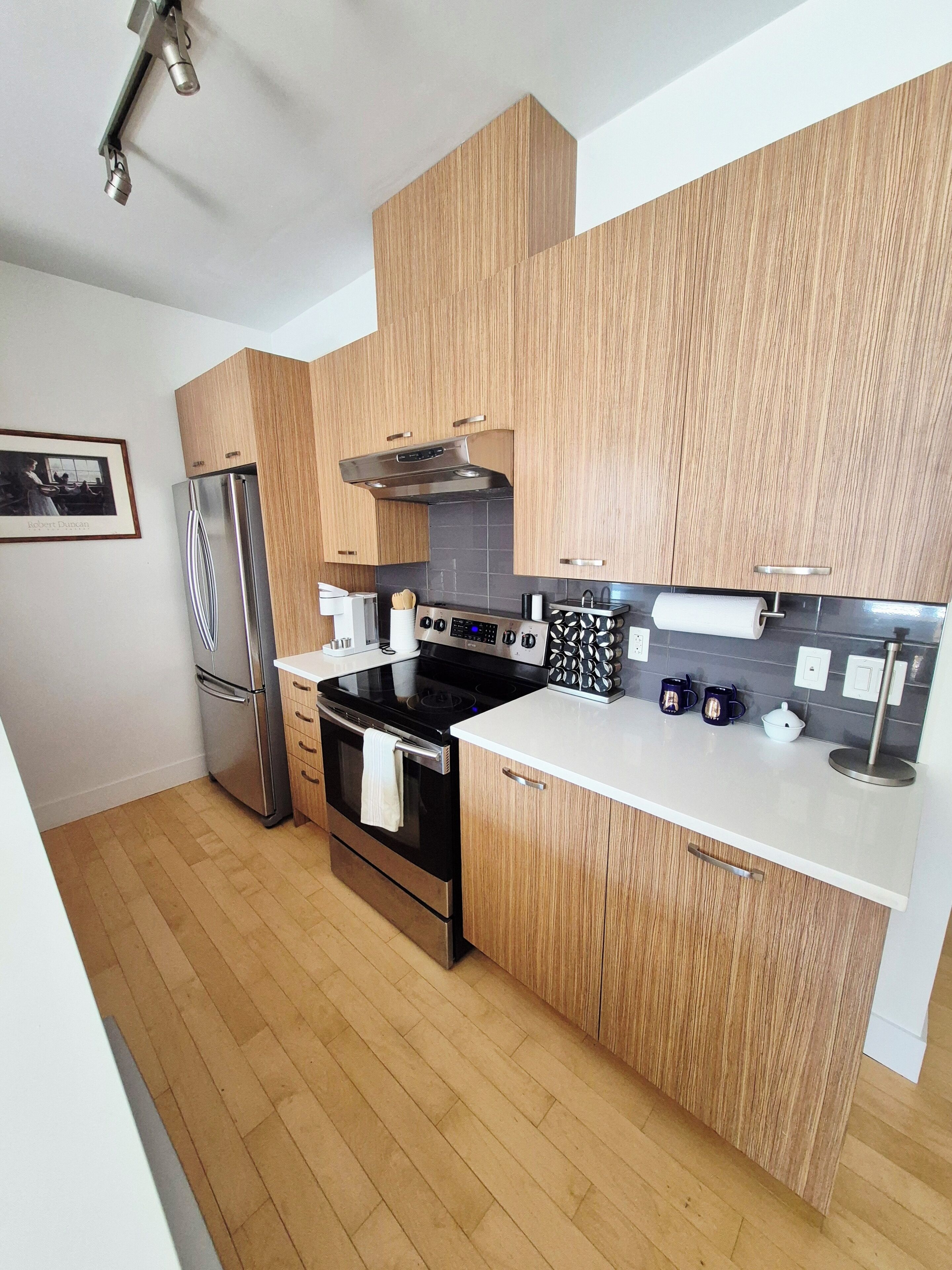 Eine moderne Küche mit Holzschränken, Edelstahlgeräten und einer weißen Arbeitsplatte.