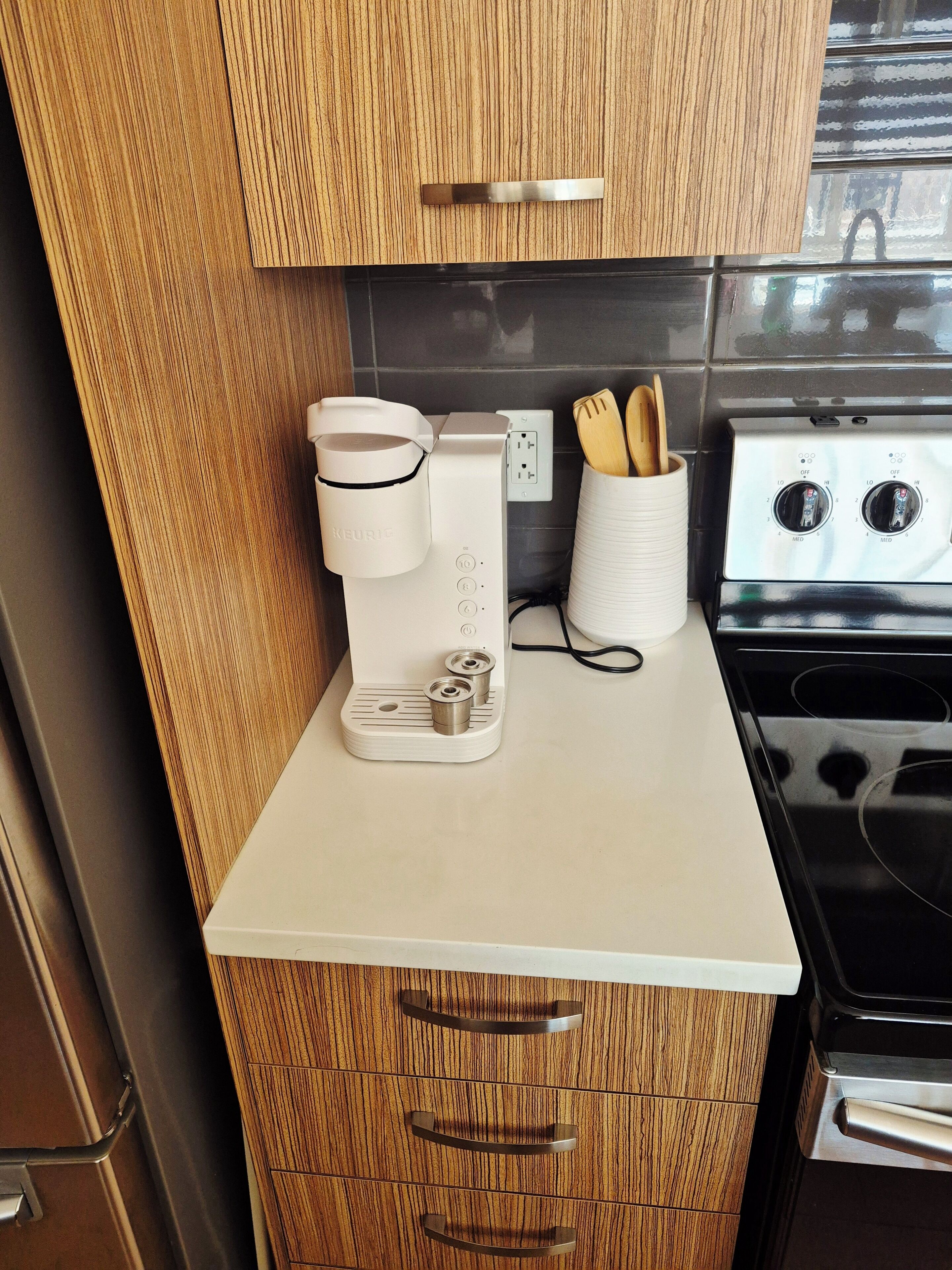 A kitchen with a coffee maker, a stove, and wooden cabinets.