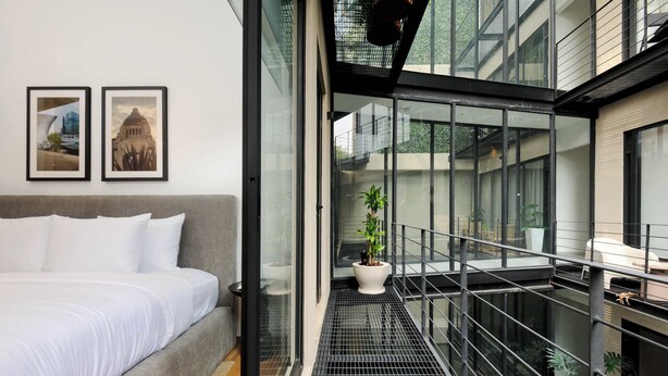 A modern hotel room with a bed, a balcony with a railing, and two framed pictures on the wall. - w* | Amazing 2BR in the Heart of Roma Sur (Ciudad de México)