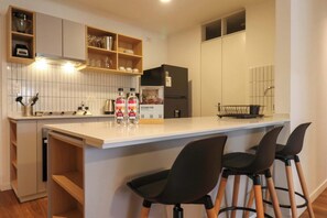 A modern kitchen with white cabinets, a black refrigerator, and a bar area with stools. - w* | Exceptional 2BR w/ Balcony in Miraflores (Miraflores)