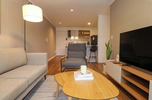 A modern living room with a sofa, a coffee table, a TV, and a kitchen in the background. - w* | Exceptional 2BR w/ Balcony in Miraflores (Miraflores)