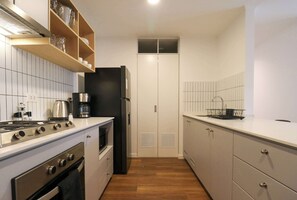 Eine kleine Küche mit Herd, Backofen und einem schwarzen Kühlschrank.