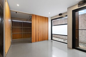 Ein modernes Interieur mit einer schiebbaren Holztür zu einem Stauraum, einer großen Garagentür und einem Betonboden.