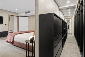Ein modernes Hotelzimmer mit Bett, Fernseher, Kleiderschrank und kleinem Tisch.