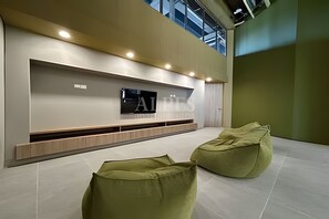 Ein modernes Interieur mit einem wandmontierten Flachbildfernseher, grünen Sitzsäcken und einem gefliesten Boden.