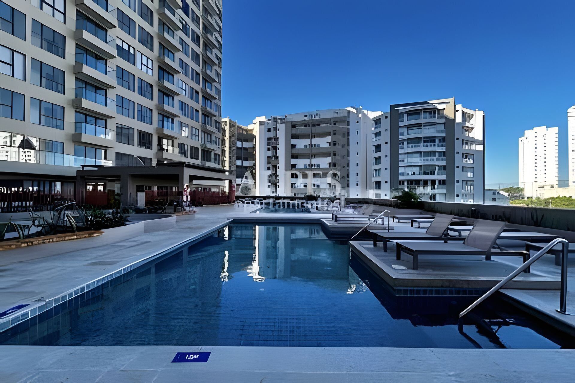Ein Pool mit Liegestühlen und Blick auf hohe Gebäude.