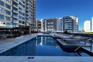 Ein Pool mit Liegestühlen und Blick auf hohe Gebäude.