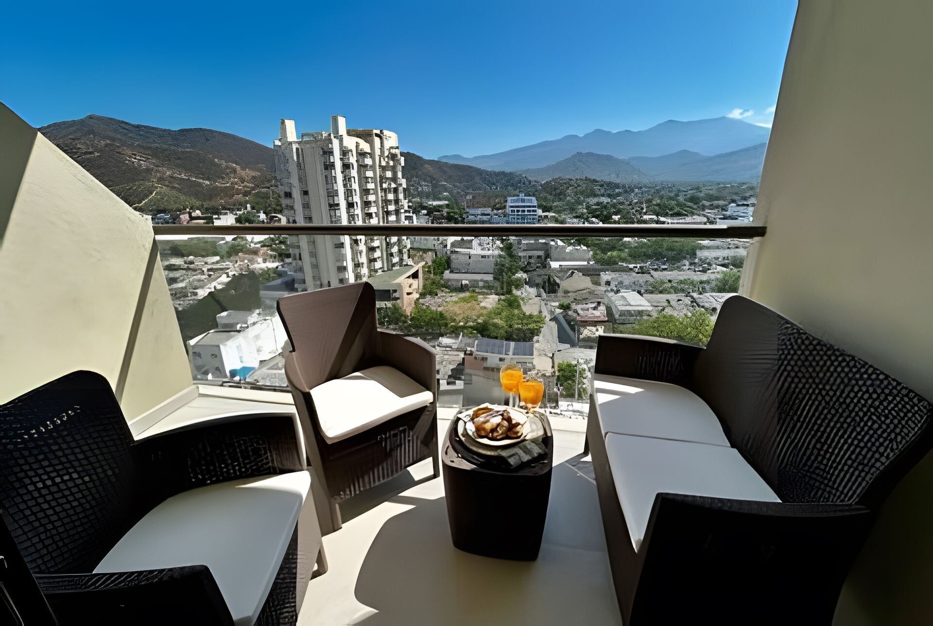 A balcony with two chairs, a small table, and a glass of orange juice.