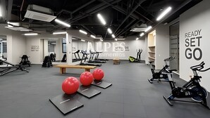 Een sportschool met trainingsapparatuur, een muur met motiverende tekst en een plafond met zichtbare balken.