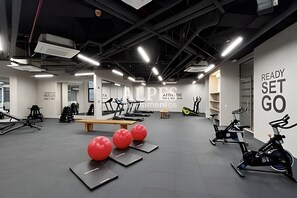 Ein Fitnessraum mit Trainingsgeräten, einer Wand mit motivierenden Texten und einer Decke mit freiliegenden Balken.