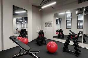 Une salle de sport équipée de matériel d’exercice, d’un banc et de ballons rouges pour faire de l’exercice.