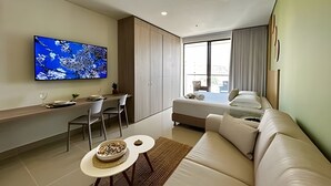 Een moderne hotelkamer met een flatscreen televisie, een bank, een eethoek en een bed.