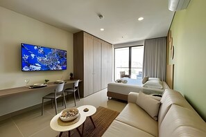 Ein modernes Hotelzimmer mit Flachbildfernseher, einer Couch, einer Essecke und einem Bett.
