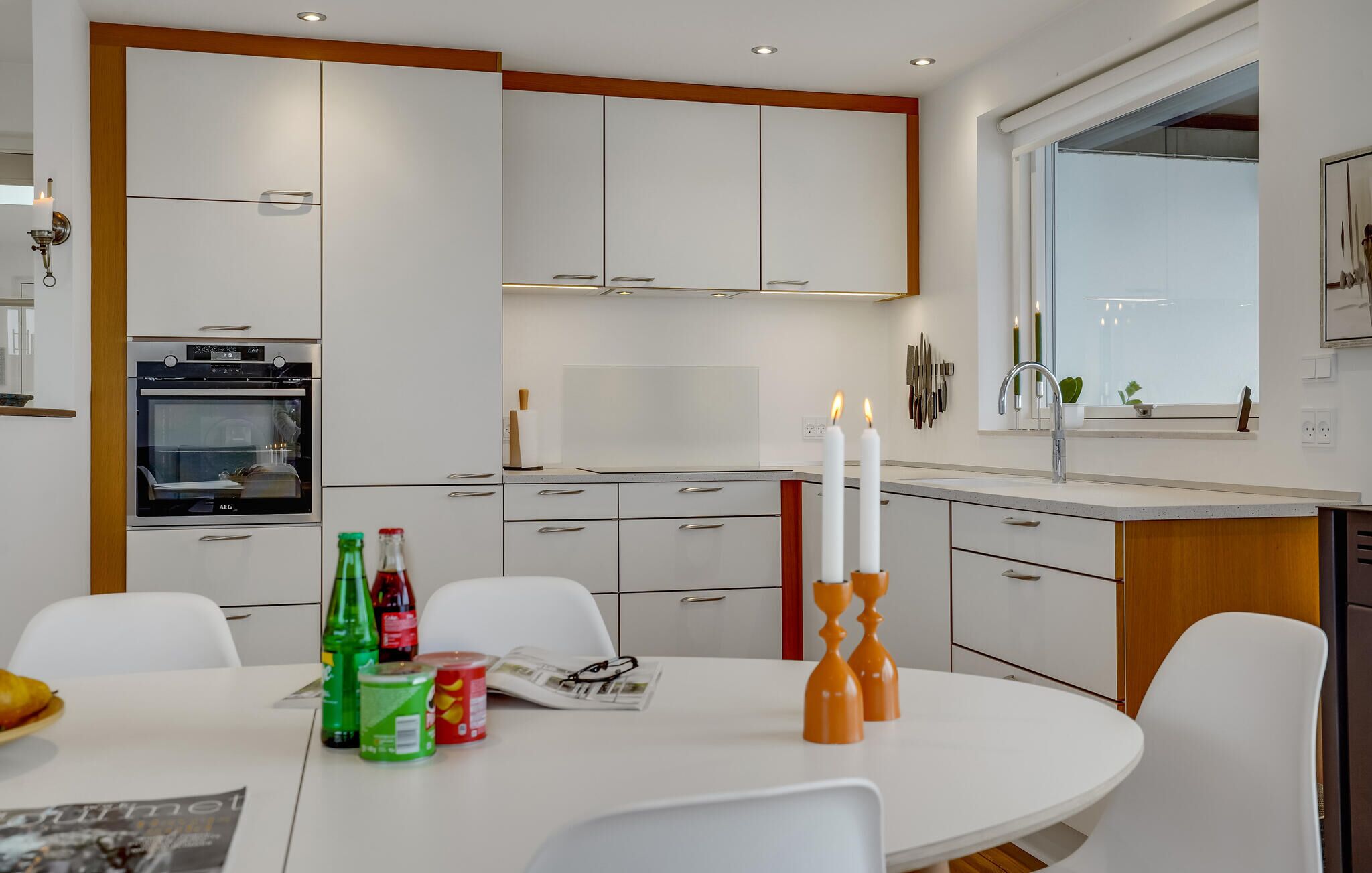 Eine moderne Küche mit weißen Schränken, einem eingebauten Backofen, einem Esstisch mit Stühlen und einem Fenster mit Blick.