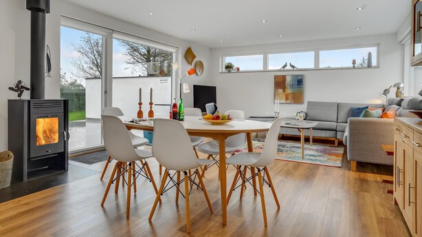 Ein modernes Wohnzimmer mit einem zentralen Esstisch, einer Couch und einem Kamin.
