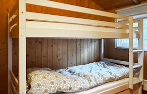 Ein Etagenbett mit einem gemusterten Bettbezug in einem Holzraum.