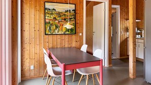 Una habitación con paneles de madera, una mesa de comedor, sillas y un cuadro en la pared.