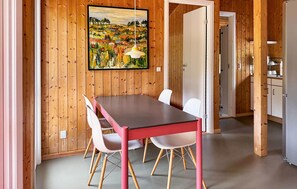 Ein Zimmer mit Holzwänden, einem Esstisch, Stühlen und einem Bild an der Wand.