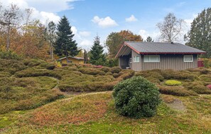 Ein Haus, umgeben von einem Garten mit verschiedenen Sträuchern und einem kleinen Teich.