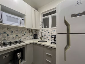 Eine Küche mit Kühlschrank, Herd, Mikrowelle und Kaffeemaschine.