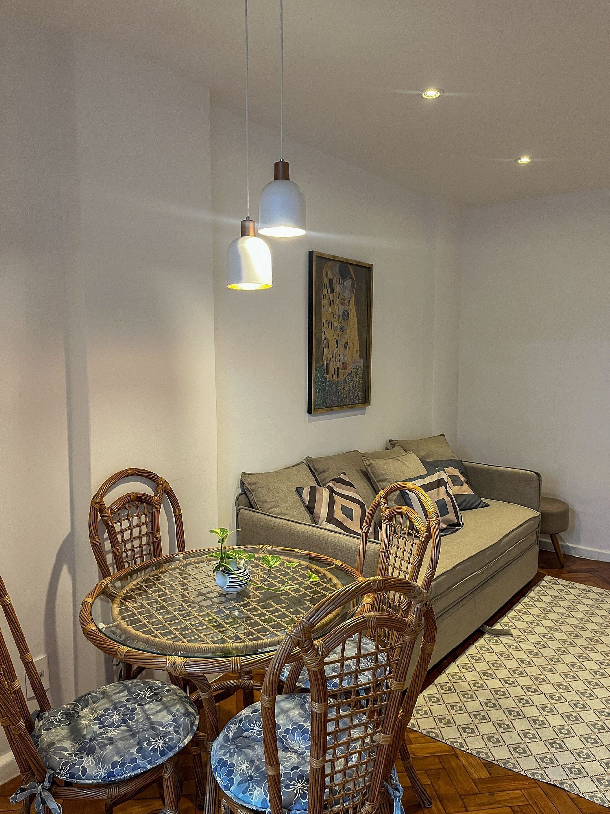 A dining area with a round table, chairs, and a hanging light fixture.