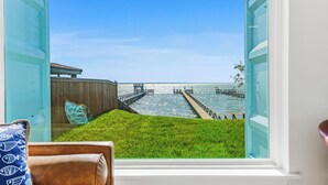 A room with a large window overlooking a pier and water.