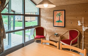 A wooden-paneled room with two red chairs, a wooden table, and a view through large windows. - Gorgeous home in Vejle with WiFi (Vejle)
